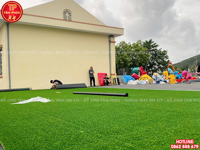 Thực hiện trải cỏ nhân tạo cho sân chơi trước khi lắp đặt đồ chơi